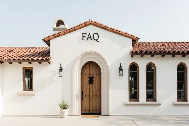 A clean, informative Spanish style home exterior used for an FAQ section, white stucco walls, terracotta roof tiles, arched doorway.