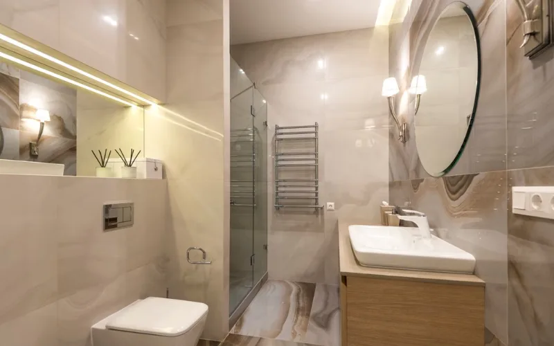 Modern beige bathroom with layered lighting fixtures.