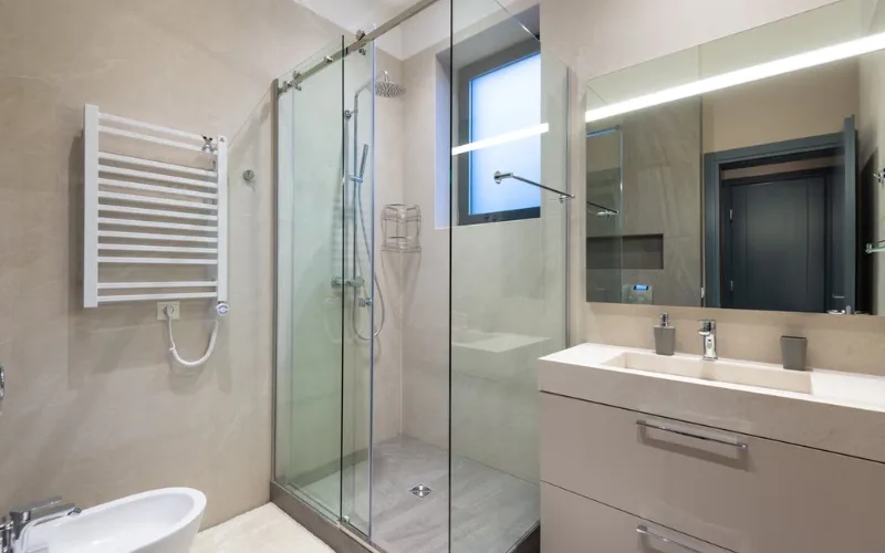 Modern beige bathroom with glass shower stall and vanity.
