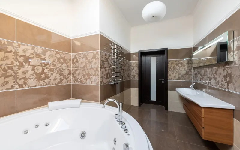 Bathroom with round whirlpool bathtub and brown floral tiles.