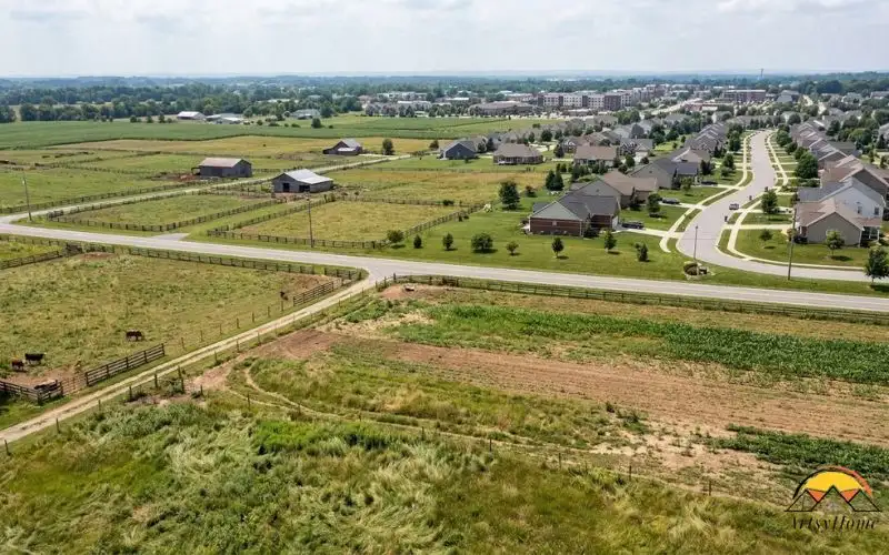 Real estate photograph showing three different land situations within one natural landscape: agricultural fields in the foreground, a rural vacant parcel farther away,